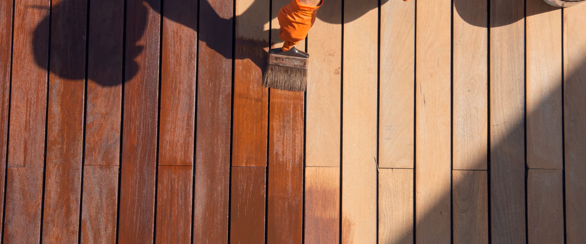 Before and after comparison of a timber deck restoration, showing weathered boards freshly re-oiled